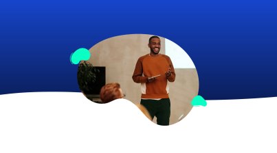 A person in an orange sweater is engaged in presentations, holding a tablet in front of a screen with an abstract blue and white background.