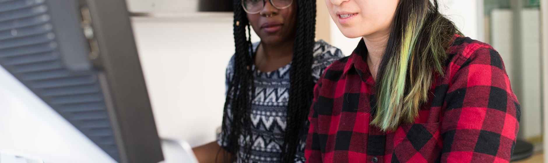 woman wearing red and black checkered blouse using macbook