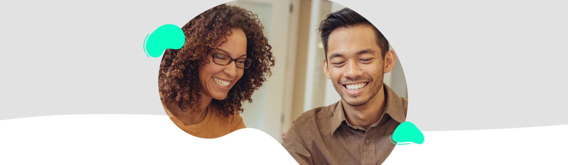 A woman and man sit together, both smiling as they look at something off-camera during the TeacherMatic Autumn Community Webinar. The scene is set against a light gray and white abstract background, capturing the essence of the latest updates and user AI insights.