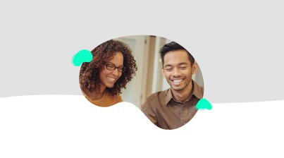 A woman and man sit together, both smiling as they look at something off-camera during the TeacherMatic Autumn Community Webinar. The scene is set against a light gray and white abstract background, capturing the essence of the latest updates and user AI insights.