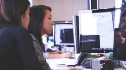 two women sitting in front of computer monitor