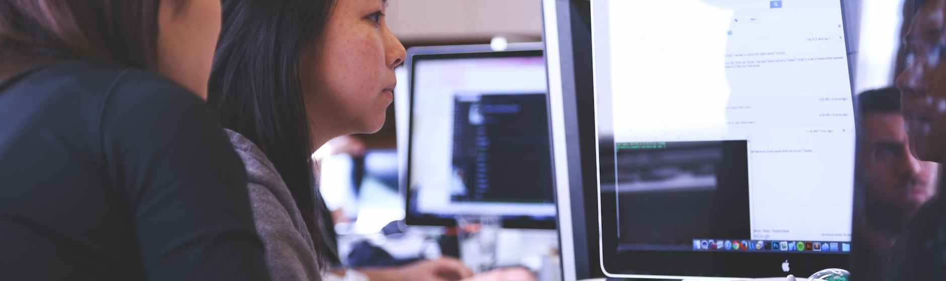 two women sitting in front of computer monitor