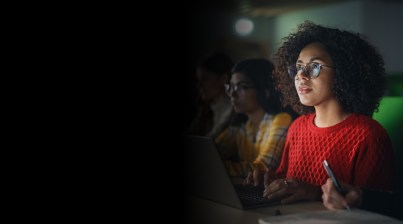 Focused individuals using laptops in a dimly lit room.