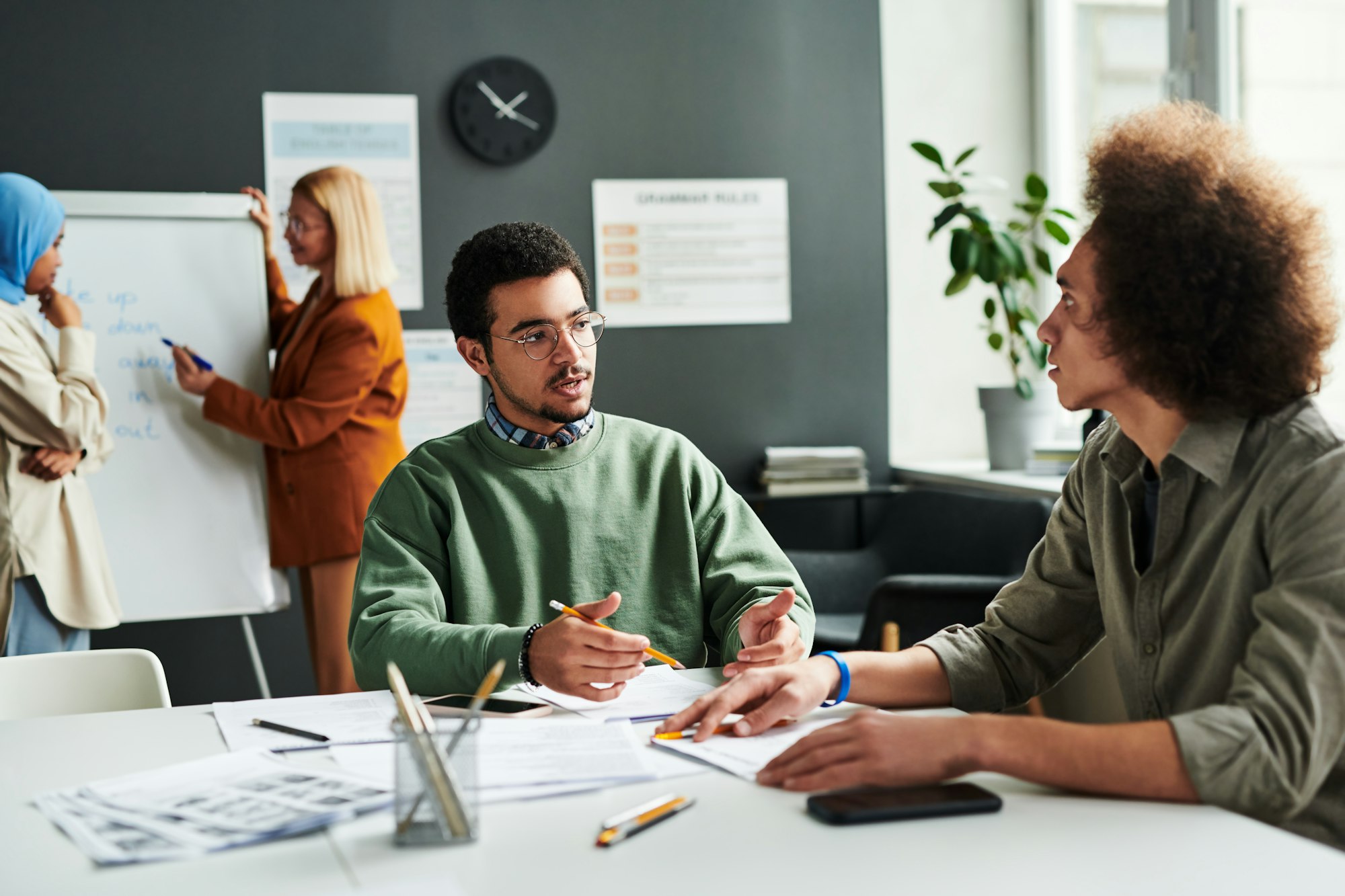 Young confident Middle Eastern male student talking to other learner