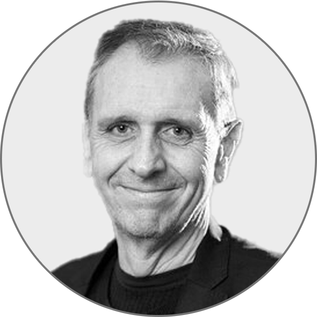 Smiling person with short hair wearing a dark jacket, set against a plain background.